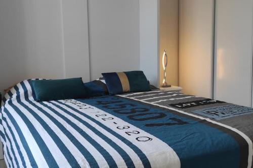 - un lit avec une couette bleue et blanche dans l'établissement Appartement T3 confortable et idéalement situé, à Concarneau