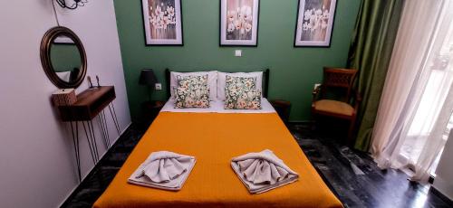 una camera da letto con un letto con una coperta arancione e uno specchio di Nancy Rooms a Skala Kallonis