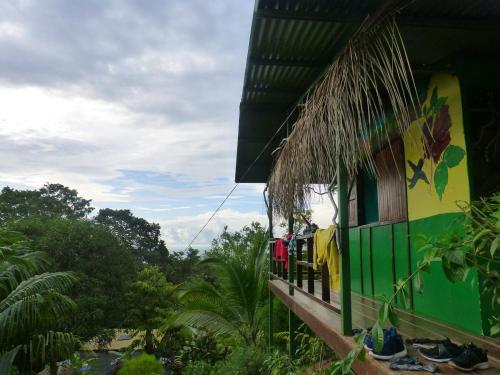 a green and yellow house with a balcony and trees at Vista Alta Ecolodge Bahia Drake in Drake