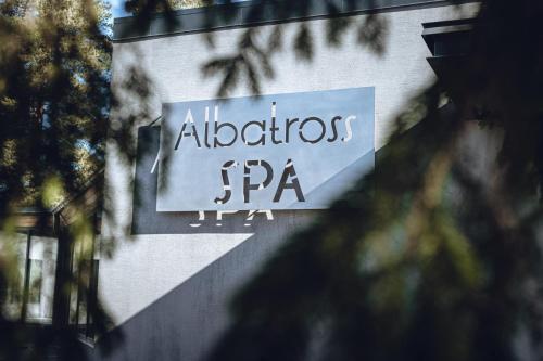 a sign on the side of a building that reads albertos at Three By The Sea apartments at Albatross Home in Ķesterciems