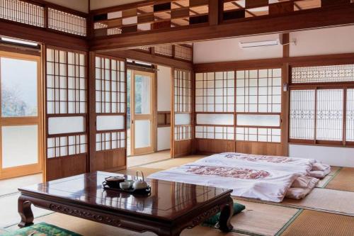 - une chambre avec un lit, une table et des fenêtres dans l'établissement 一棟貸し古民家宿「縁側のとき」Engawanotoki Villa, 