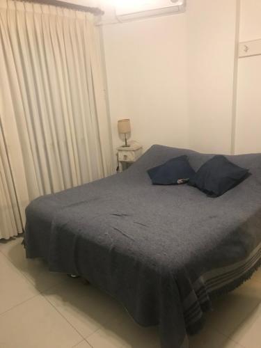 a bedroom with a bed with a gray blanket and curtains at Monoambiente cómodo in Buenos Aires