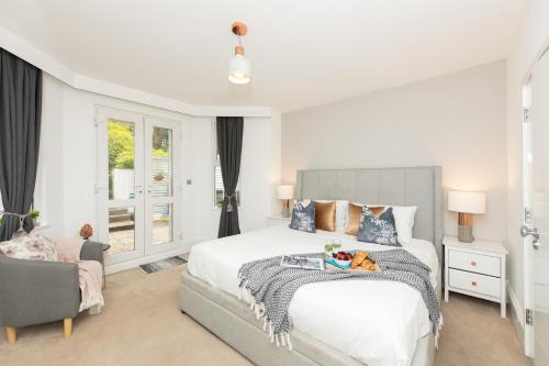 ein Schlafzimmer mit einem großen weißen Bett und einem Stuhl in der Unterkunft Stylish Apartment with BBQ Kensington in London