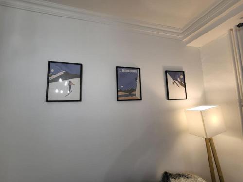 a room with four pictures on the wall and a lamp at Appartement Aroma Snow in Briançon