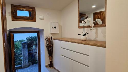 een keuken met witte kasten, een spiegel en een raam bij Sabi2 in Mošćenička Draga