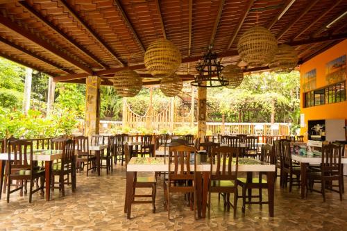 a dining room with tables and chairs and trees at Apart Hotel Acuarious de Luis in Estelí