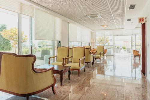 una sala de espera con sillas, mesas y ventanas en Fishta Hotel & Apartments, en Velipojë