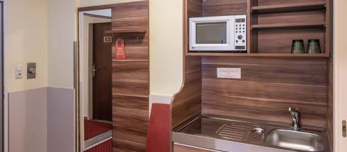a small kitchen with a microwave and a sink at Hotel Kufsteinerhof in Kufstein