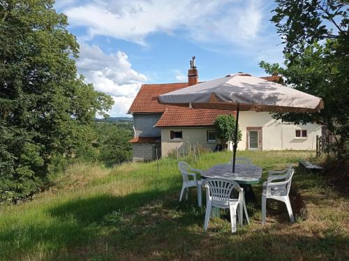 a table with chairs and an umbrella in a field at Chez Ophélie in Saint-Bazile-de-Meyssac