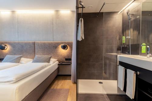 a small bathroom with a bed and a shower at arte Hotel Salzburg in Salzburg
