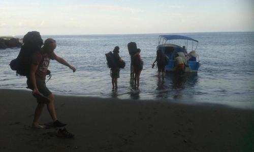 a group of people standing on the beach near a boat at Vista Alta Ecolodge Bahia Drake in Drake