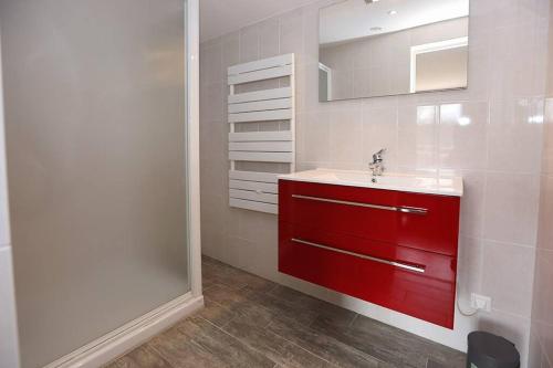 La salle de bains est pourvue d'un lavabo rouge et d'un miroir. dans l'établissement Gîte Ô fil du Tarn, à Lescure-dʼAlbigeois
