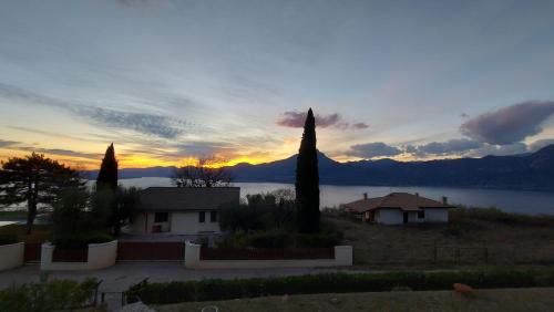 a sunset over a lake with a house and trees at Garda Panoramic House in Albisano