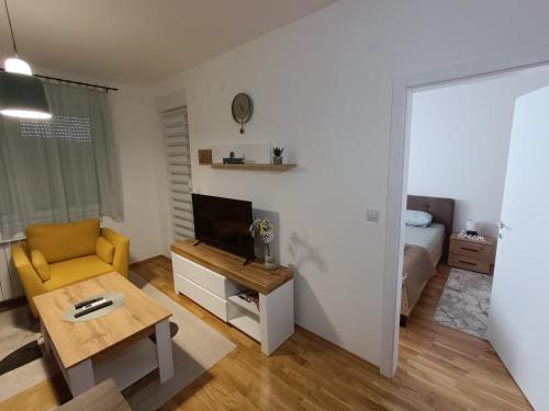 un soggiorno con sedia gialla e TV di Apartment Eight - Pirot a Pirot