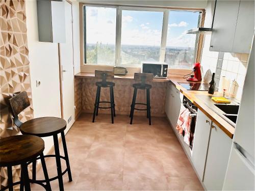 eine Küche mit Hockern und einer Theke mit einem Fenster in der Unterkunft Spacieux et confortable appartement en résidence in Pontoise