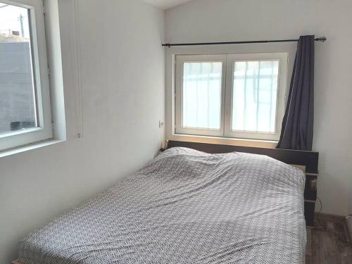 uma cama num quarto com duas janelas em Maisonnette avec terrasse privative em La Ciotat
