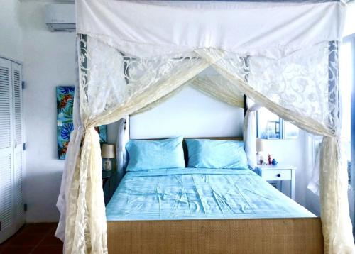 a bedroom with a canopy bed with blue pillows at CasaDePlaya Cabarete Beachfront in Cabarete