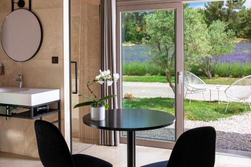 a bathroom with a table and chairs and a window at La Bastide de Damien, 5 clefs Demeure d'Exception et Table Remarquable dans le guide Teritoria, JACUZZI Privatif, Cuisine étoilée Dominique Frérard in Aix-en-Provence