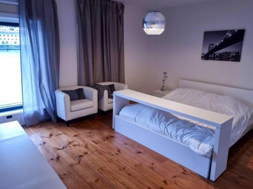 a bedroom with a white bed and a chair at Central duplex apartment-full view of Douro river in Vila Nova de Gaia