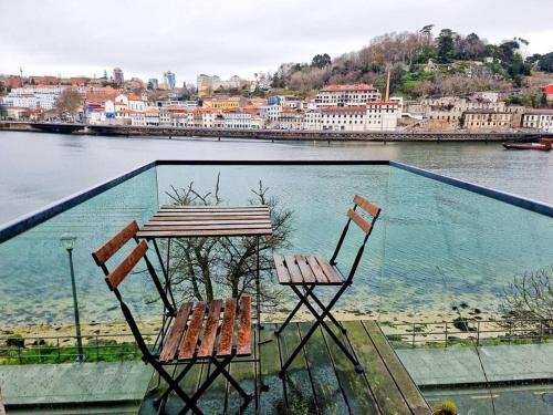 two chairs and a table on a balcony with the water at Central duplex apartment-full view of Douro river in Vila Nova de Gaia
