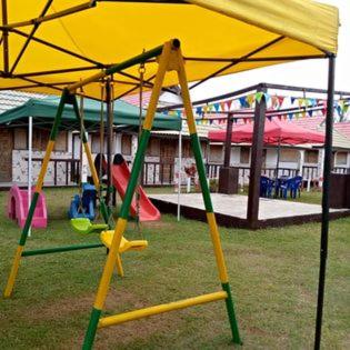 a playground with a yellow umbrella and swings at Bungalow le Charme, au bord de la mer in Marofarihy