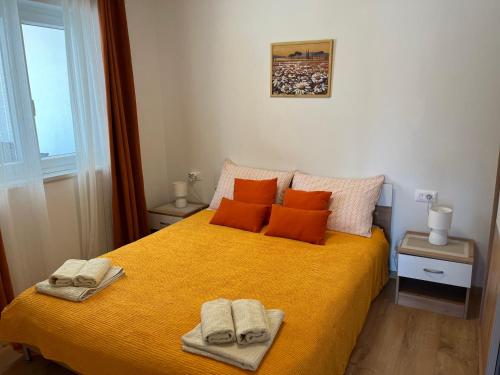a bedroom with a yellow bed with two towels on it at Apartments Zahtila - Pina in Rabac