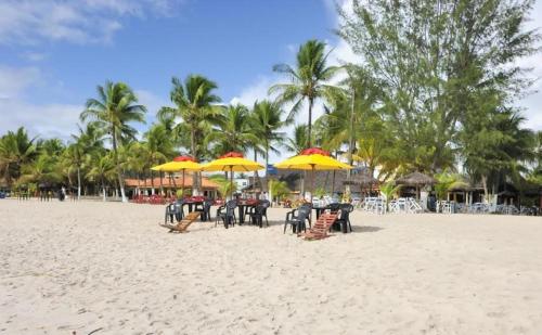 a beach with tables and chairs with yellow umbrellas at Bimba Chalés Pé na Areia - Guaibim-Ba in Guaibim