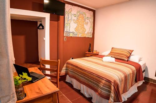 a bedroom with a bed and a table with a laptop at Hotel Boutique Mosaico in Granada