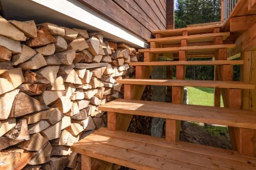 a log cabin with wooden stairs next to a pile of logs at Almhaus Gensbach in Innerkrems