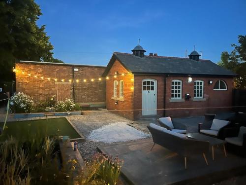 a brick house with a couch in a yard at Cosy small cottage in Wirral Merseyside with kitchen in Lower Bebington