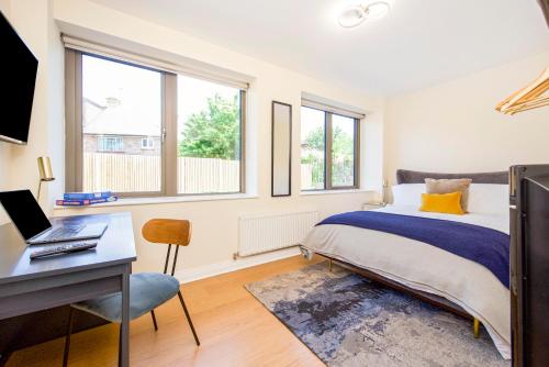 a bedroom with a bed and a desk with a laptop at Prime Luxury, Heathrow, FreeParking, WiFi, Netflix in Yiewsley