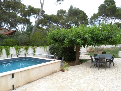 une terrasse avec une piscine, une table et des chaises dans l'établissement Villa à 80m de la mer, à La Seyne-sur-Mer