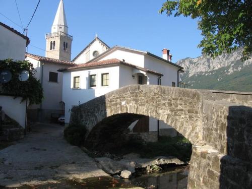 a bridge over a river in front of a building at Guest House Žerjal in Podnanos