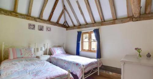 a bedroom with two beds and a window at Charming picturesque cottage - nr Tenterden & Rye, pets welcomed in Rolvenden