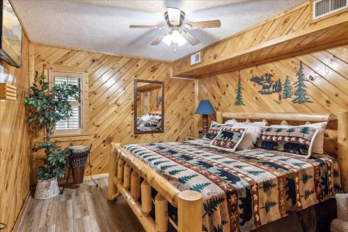 Dormitorio en cabaña de madera con cama y ventilador de techo en Smokey Max Chalet, en Sevierville