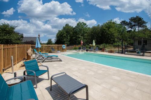 une piscine avec des chaises bleues et une piscine dans l'établissement ROCHE-LOIRE, à Le Thoureil