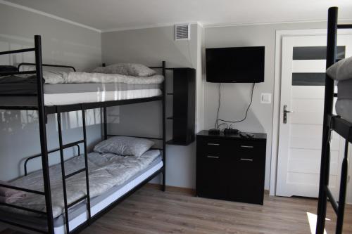 a room with three bunk beds and a television at Apartament Zacisze in Iława