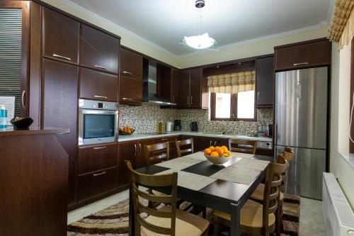 eine Küche mit Holzschränken und einem Tisch mit einer Schüssel Orangen in der Unterkunft Katerina & Elia's Family House in Leonidi
