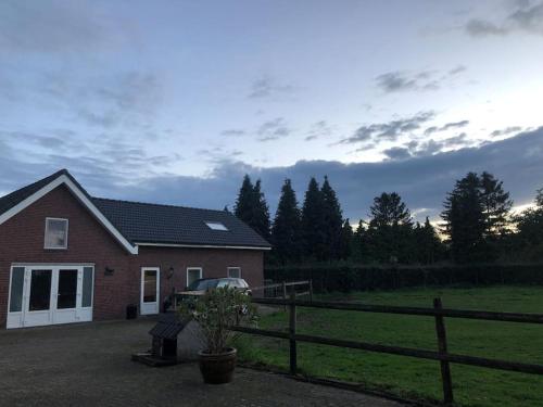 a house with a fence next to a field at Charming authentic renovated farm in Cadier en Keer