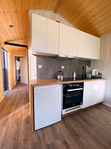 a kitchen with white cabinets and a stove at Wypoczynkowo Domki Letniskowe in Mikołajki