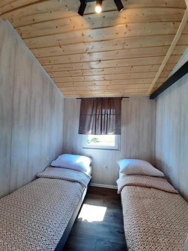 2 Betten in einem kleinen Zimmer mit Fenster in der Unterkunft Wypoczynkowo Domki Letniskowe in Mikołajki