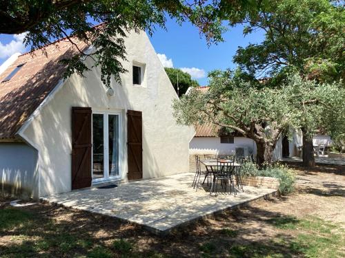una casa bianca con un tavolo e sedie di fronte di Maison conviviale avec jardin à Saint-Nazaire-de-Pézan a Saint-Nazaire-de-Pézan