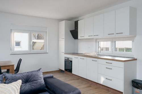a kitchen with white cabinets and a blue couch at Number One Apartments in Vir
