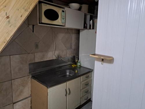 a small kitchen with a sink and a microwave at Quarto privativo, banheiro externo. in Novo Hamburgo