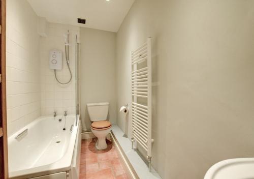 a bathroom with a toilet and a tub and a sink at Ruth's in Charminster