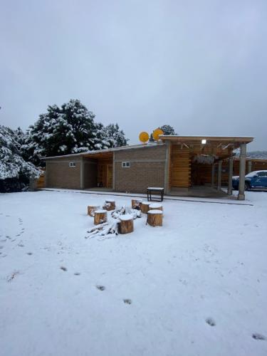 a snow covered yard with a building with a bench at Cabañas Rochivo Ranch in Creel