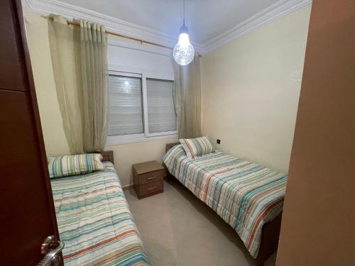 a bedroom with two beds and a window at Appartement de vacances piscines et plage in Tangier