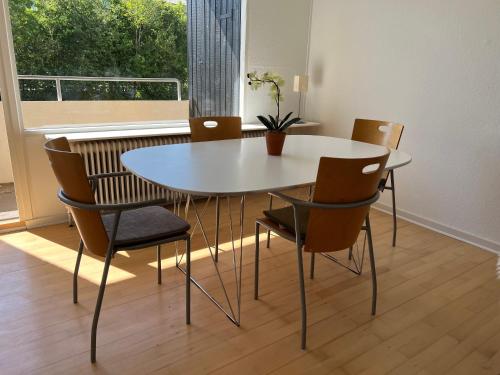 una mesa y sillas blancas en una habitación con ventana en Stor 2 værelses lejlighed, en Randers