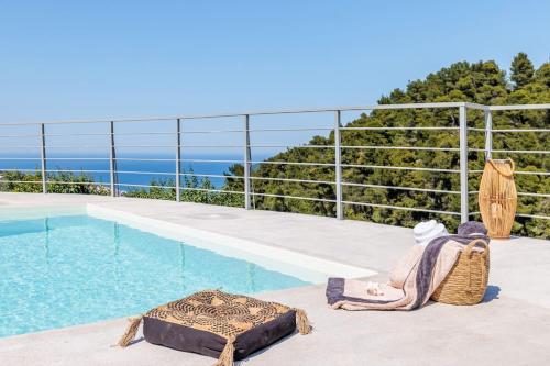 a swimming pool with a chair and a mattress next to a pool at Villa Koukounaria in Skopelos Town
