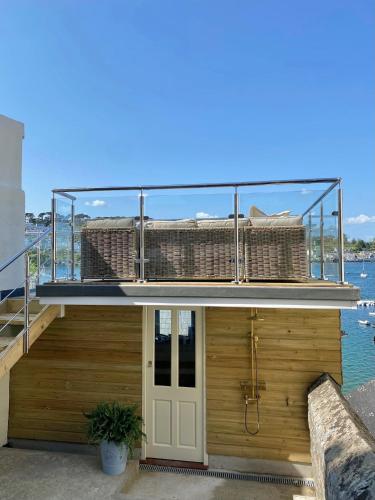 a house on the water with a balcony at Enchanting Harbourside Cottage with Panoramic Views in Polruan